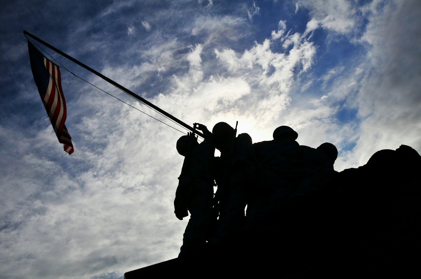 Soldiers raising the American flag on a stone monument.