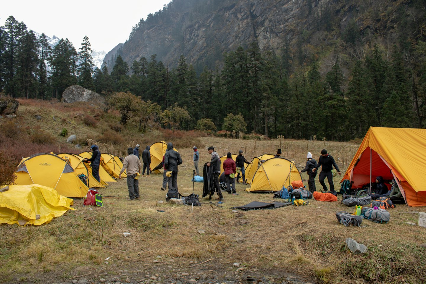 People set up camping tents in a rocky mountain meadow.