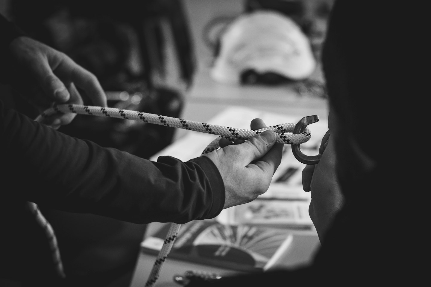 Hands tying a knot in a patterned rope and carabiner.